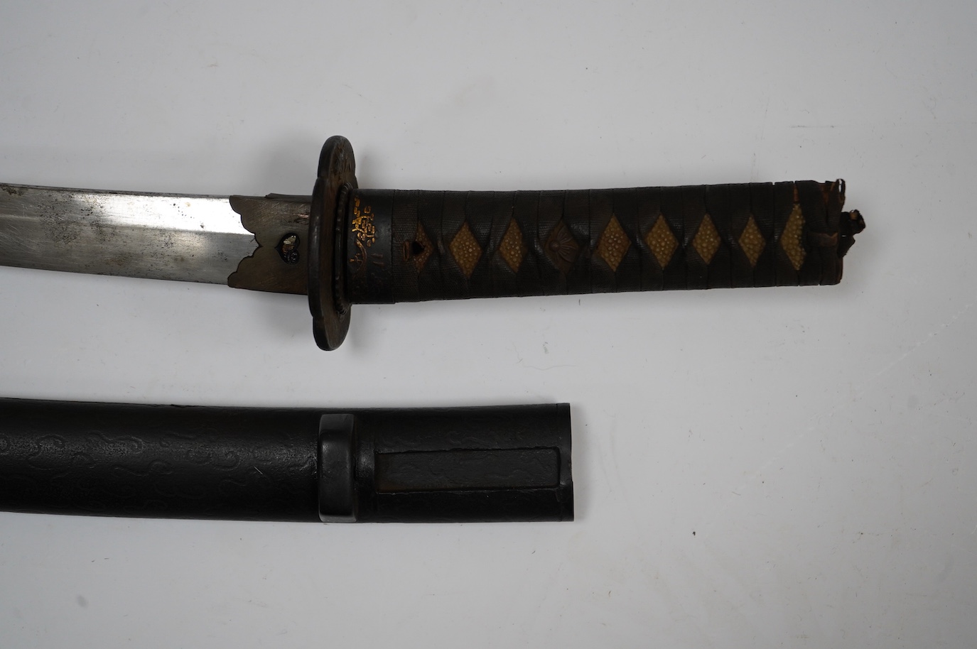 A Japanese short sword wakizashi, blade 42.5cm unsigned, iron mokko tsuba with inlaid details, tape bound same tsuka, with iron fuchi (kashira missing) in its black lacquered saya. Condition - poor to fair.